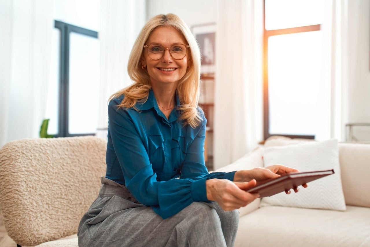 Psicóloga infantil sentada en un sofá con un libro en las manos.